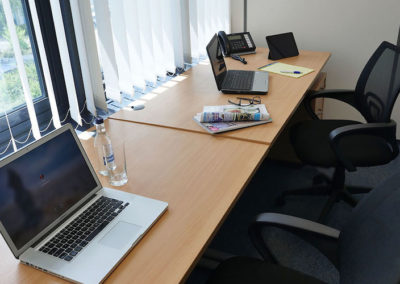 2 desks with laptop on the tables and looking out of a large window.