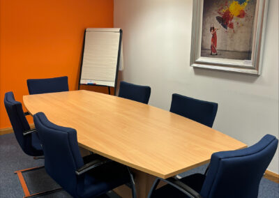 Meeting room for 6 people with an orange wall and a flip chart