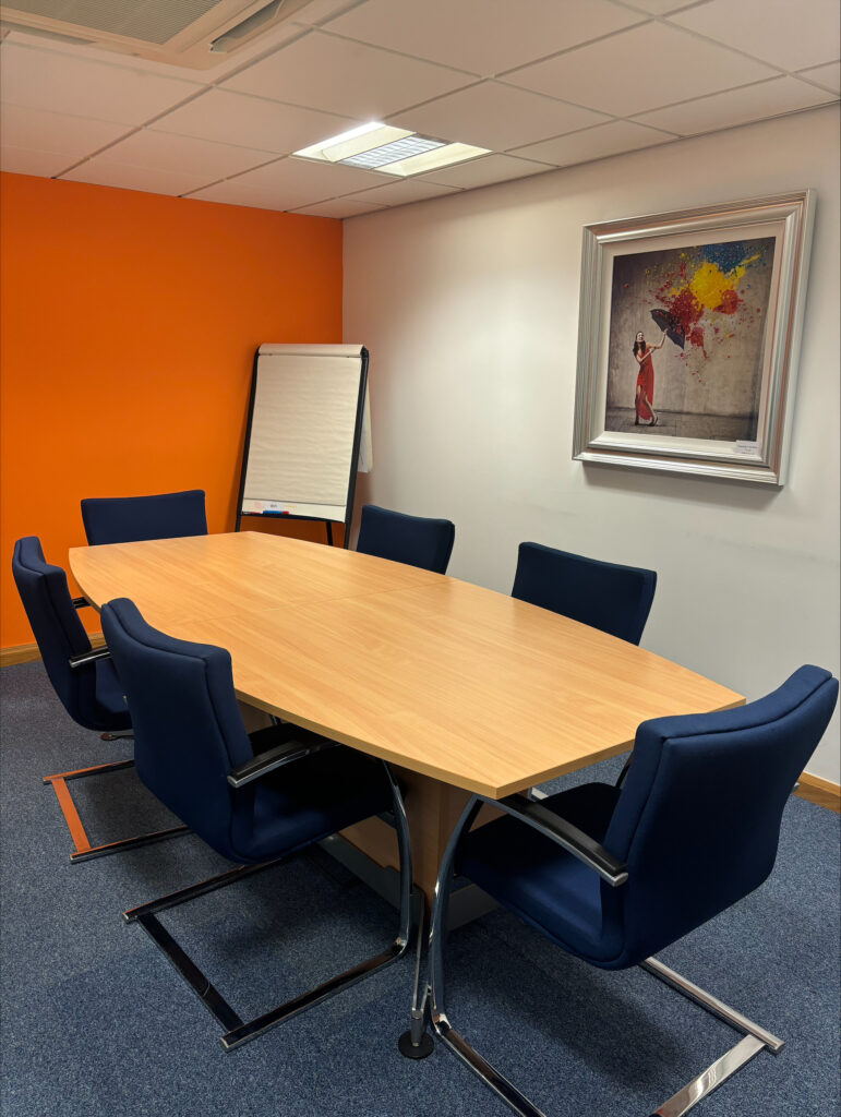 Meeting room for 6 people with an orange wall and a flip chart
