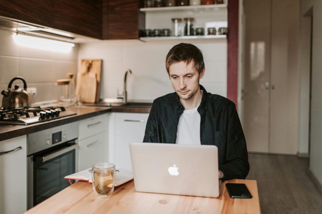 Remote workers sat working on his own in his kitchen.