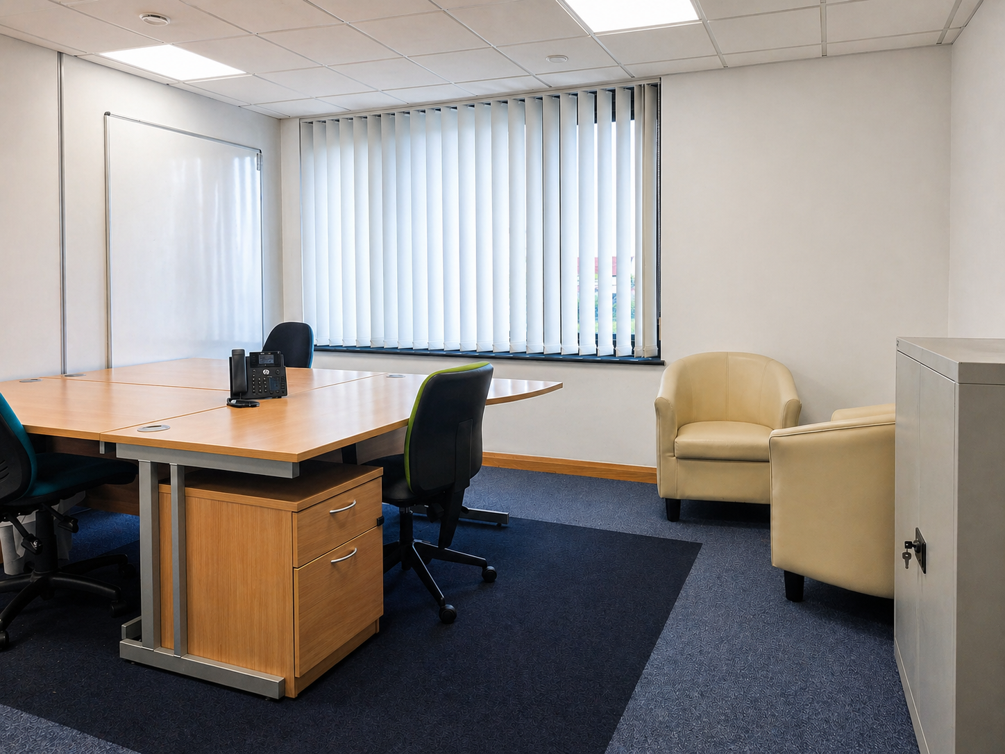 3 desk office with some bucket chairs placed at the side set up as a meeting area