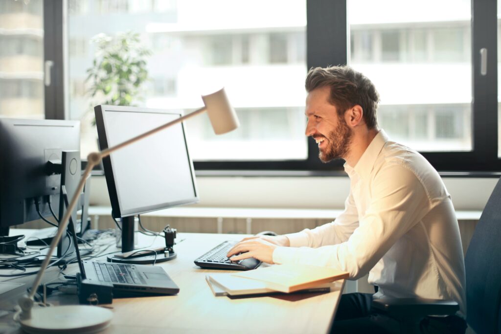 Man smiling at his computer screen. 